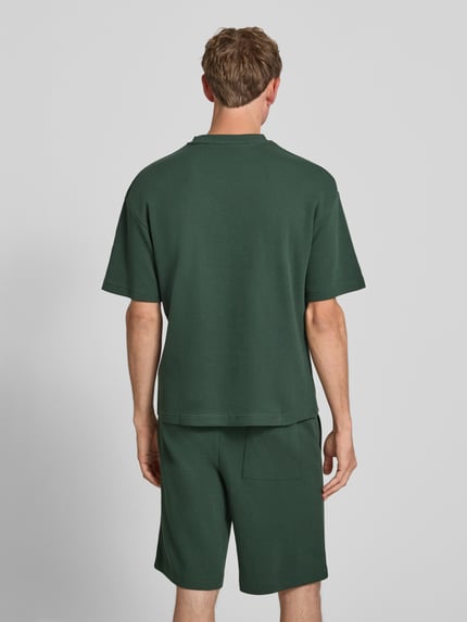 Męski model nosi T-Shirt mit Strukturmuster und Label-Stitching od PROHIBITED z bawełny, krój regular fit, kolor ciemnozielony, fakturowany wzór, okrągły dekolt, brustasza, długość tyłu w rozmiarze M: 64 cm, całkowita sylwetka widok z tyłu.
