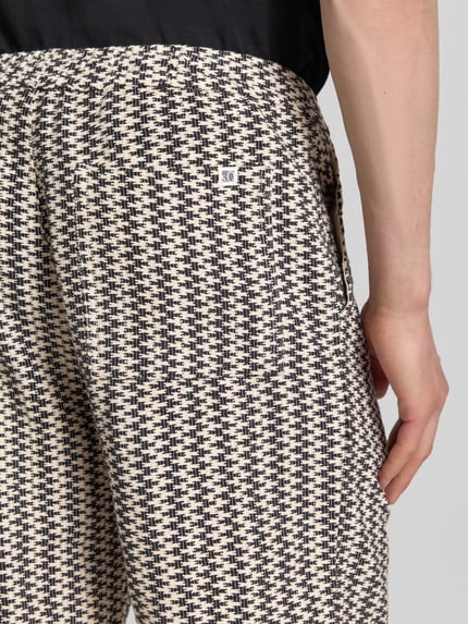 Männermodel trägt Relaxed Fit Stoffshorts aus Baumwoll-Mix von s.Oliver RED LABEL mit Optik: Allover-Muster, Strukturmuster, Label-Patch, seitliche Eingrifftaschen und Gesäßtasche aus reine Baumwolle, Nahaufnahme Gesäßtasche.