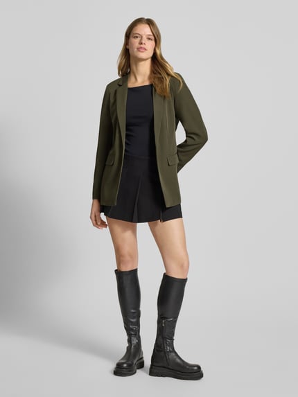 Kobiece modelka nosi Loose Fit Longblazer mit Abnähern Model 'BOZZY' od Pieces, efekt: jednolity kolor, krój loose fit, kołnierz z połami, długi rękaw, kieszenie z patką, wyhaftowane logo, bez zapięcia, całkowity widok z przodu.