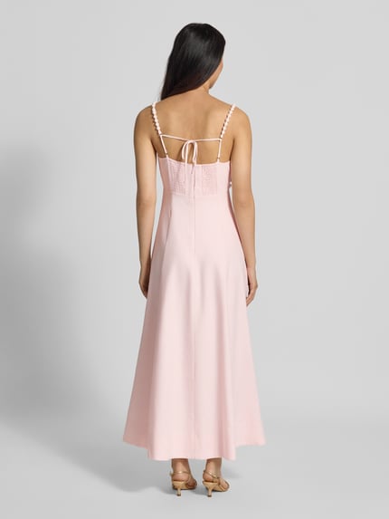Frauenmodel trägt Abendkleid aus Leinen-Viskose-Mix Modell 'Nicolette' von Forever New in Rosa mit Spaghettiträgern, Ganzkörperansicht Rückansicht. Taillierte Passform, Karree-Ausschnitt, florale Zier-Applikation, Midilänge, rückseitiger Nahtreißverschluss und Smok-Einsatz.