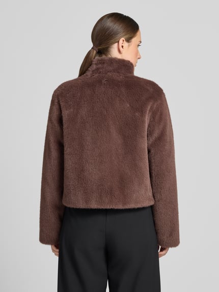 Frauenmodel trägt Jacke aus Kunstfell mit Zweiwege-Reißverschluss von Marc Cain in Braun, Regular Fit, Stehkragen, Rückenansicht, KI-modifiziertes Bild.