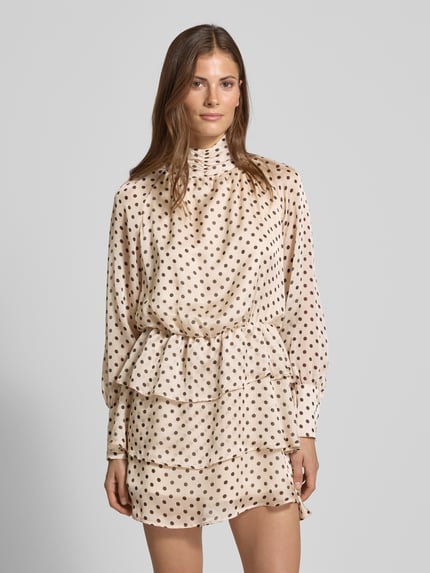 Frauenmodel trägt Cocktailkleid im Stufen-Look mit Stehkragen von Rinascimento, cremefarben mit braunen Punkten, Satin, tailliert, Minikleid, Ganzkörperansicht von vorne.