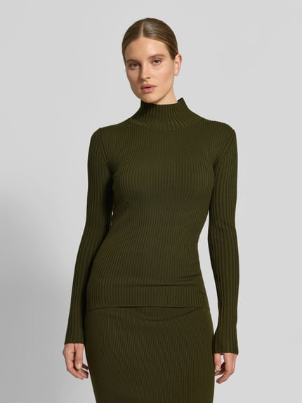 Frauenmodel trägt Longsleeve aus Woll-Mix von Victoria Beckham, grün, eng anliegend, Ripp- und Strick-Optik, Stehkragen, Nahaufnahme Oberkörper.