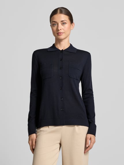 Frauenmodel trägt Strickjacke aus reiner Schurwolle Modell 'DETTO' von MM by Max Mara, dunkelblau, glatte Textur, Nahaufnahme Oberkörper.
