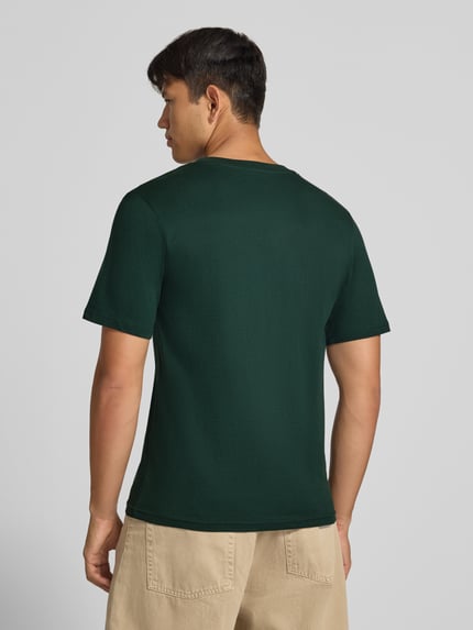 Męski model nosi Regular Fit T-Shirt aus reiner Baumwolle mit Label-Detail von JACK & JONES w kolorze ciemnej zieleni, bawełna, krój regular fit, okrągły dekolt, detal z logo, Długość tyłu w rozmiarze M: 67 cm, Ganzkörperansicht Rückansicht