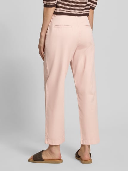 Frauenmodel trägt Chino mit Paspeltaschen am Gesäß von Jake*s Casual in zartem Rosa, Relaxed-Fit, verkürzte Passform, Ganzkörperansicht Rückansicht. Bundweite bei Größe 36: 37 cm, Innenbeinlänge bei Größe 36: 68 cm, mit Eingrifftaschen und Paspeltaschen am Gesäß.