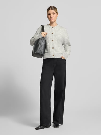 Frauenmodel trägt Cardigan mit aufgesetzten Taschen von Christian Berg Woman in unifarbener Strickoptik, Struktur, Ganzkörperansicht von vorne.