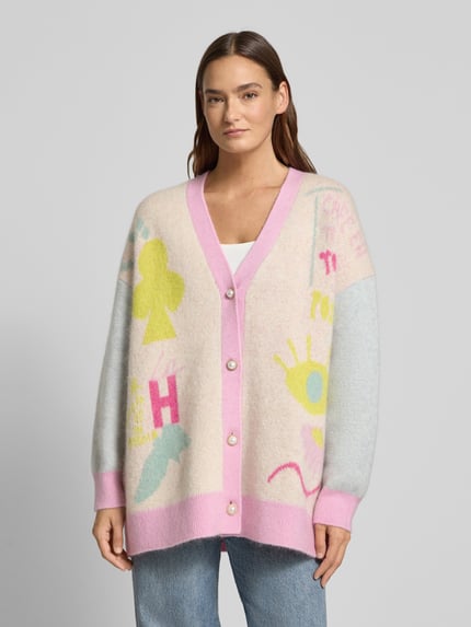 Frauenmodel trägt Cardigan aus Woll-Mix mit V-Ausschnitt und Knopfleiste von Herzensangelegenheit, Relaxed Fit, bunte Muster, Ganzkörperansicht von vorne.