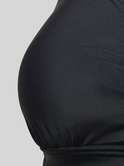 Frauenmodel trägt Bikini-Top mit Cut-Out Modell 'Lolo' von LASCANA aus elastischem Materialmix in Schwarz, Nahaufnahme Oberkörper.