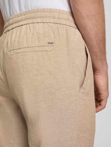 Mannenmodel draagt Tapered Leinenhose aus Baumwoll-Leinen-Mix Modell 'LINUS' van Only & Sons in melange optiek met elastische tailleband, zij- en achterzakken, katoen-linnenmix, detailopname achterkant.