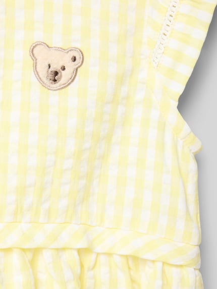 Mädchen trägt Regular Fit Kleid mit Logo-Detail von Steiff aus Reine Baumwolle, gelb-weiß kariert, Rüschenbesatz, Ärmelloses-Design, Detailaufnahme.