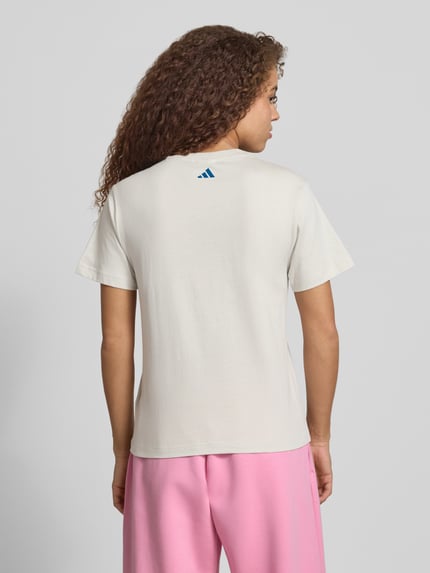 Frauenmodel trägt T-Shirt mit Label-Print von adidas Sportswear aus Reine Baumwolle, Regular-Fit, hell, Rückenlänge 61 cm, Ganzkörperansicht Rückansicht.