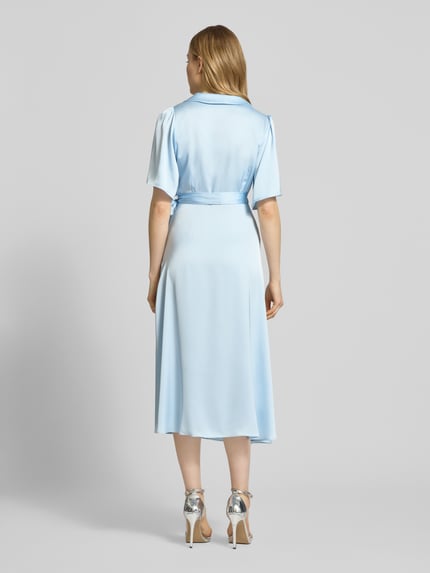 Kobiece modelka nosi sukienkę midi z satyny, taliowany fason, kopertowy styl, model 'VIENNA RAVENNA' od Vila, jasnoniebieski; zdjęcie całej sylwetki z tyłu. Długość tyłu w rozmiarze 36: 125 cm, szerokość w rozmiarze 36: 50 cm, długość rękawów w rozmiarze 36: 30 cm.
