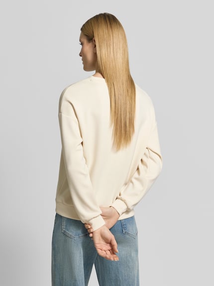 Vrouwenmodel draagt Regular Fit sweatshirt met siersteentjes model 'Banu' van Soyaconcept in crème, elastische materiaalmix met modal, ronde hals, elastische boorden, dames sweatshirt, rugaanzicht volledige lichaamsweergave.