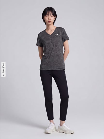Frauenmodel trägt Regular Fit Sport-T-Shirt mit LOGO-Print Modell 'Tech SSV- Twist' von Under Armour in Dunkelgrau zu schwarzer Hose, Damen Sport-T-Shirt von Under Armour, Ganzkörperansicht von vorne.