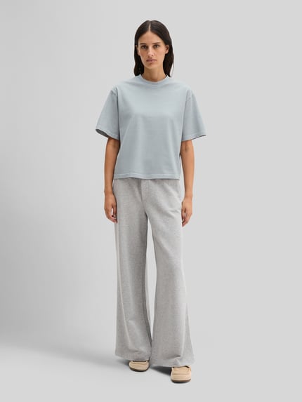 Frauenmodel trägt Boxy Fit T-Shirt aus reiner Baumwolle von Marc O'Polo, Optik: Unifarben, Passform: Boxy-Fit, Label-Schriftzug, Rundhals, Ärmelform: Kurzarm, Damen T-Shirt, Material: Reine Baumwolle, helle Farbtöne, glatte Textur, Ganzkörperansicht von vorne.