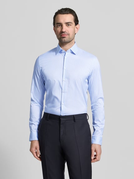 Männermodel trägt Slim Fit Businesshemd mit Kentkragen von Jake*s, hellblau-weiß gestreift, elastisch, Knopfleiste, Ganzkörperansicht von vorne.