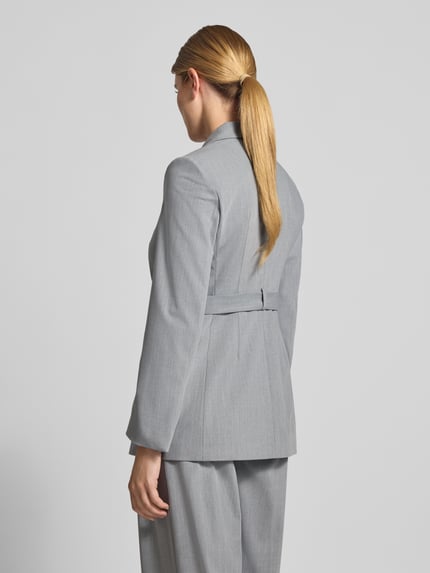 Frauenmodel trägt Eleganter Blazer mit Bindedetail - curated by Viky Rader von Style Icon Collection in Hellgrau, glatte Struktur, Ganzkörperansicht Rückansicht. Material-Mix mit Viskose-Anteil, Slim fit, taillierte Passform, Reverskragen, Pattentaschen, Knopfverschluss mit Bindedetail.
