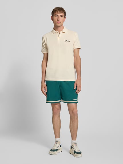 Männermodel trägt zielone szorty z siateczki Shorts mit Label-Stitching und elastischem Bund von PROHIBITED, krój relaxed fit, szerokość w rozmiarze M: 41 cm, długość wewnętrzna nogawki: 18 cm, Ganzkörperansicht von vorne.