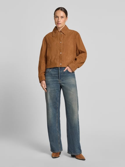 Kobiece model prezentuje kurtka skórzana Regular Fit Lederjacke aus echtem Ziegenleder Modell 'C_SALISA 60' od BOSS Orange w kolorze brązowym oraz niebieskie spodnie dżinsowe, matowa faktura, Ganzkörperansicht von vorne.