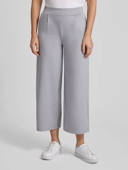 Frauenmodel trägt Wide Fit Stoffhose mit Viskose-Anteil Modell 'Kate' von ICHI in Hellgrau, Bundfalten, elastischer Bund, Ganzkörperansicht von vorne.