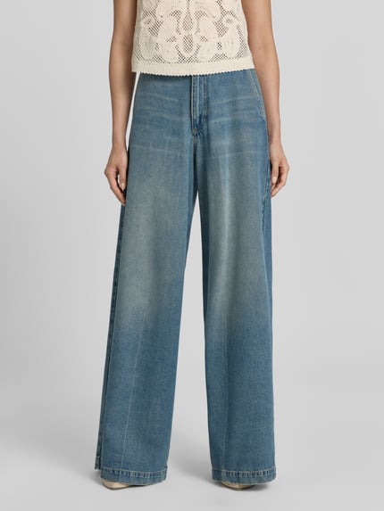 Frauenmodel trägt Regular Fit Baggy Jeans aus Baumwoll-Lyocell-Mix Modell 'CENTRAL' von BOSS in Denim-Optik mit 5-Pocket-Design, Label Patch, Knopf und verdecktem Reißverschluss, mittlere Waschung, ganzkörperansicht von vorne.