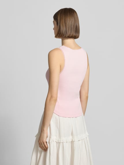 Frauenmodel trägt Tanktop in Ripp-Optik Modell 'Jolie' von OH APRIL, hellrosa, Baumwoll-Elasthan-Mix, Spitzenbesatz, Ganzkörperansicht Rückansicht.