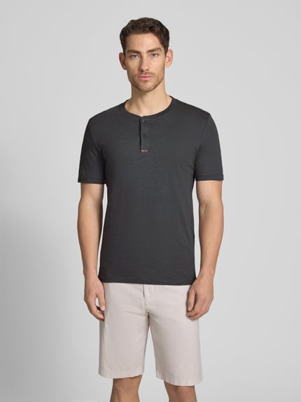 Männermodel trägt Regular Fit T-Shirt aus reiner Baumwolle von s.Oliver RED LABEL, Optik: Unifarben, Henley-Kragen, Kurzarm, Ganzkörperansicht von vorne.