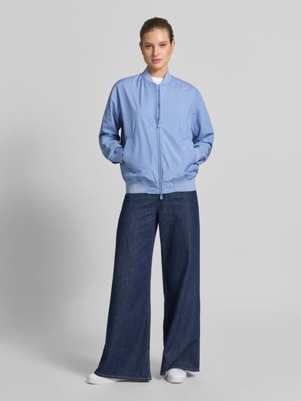 Modelka nosi Jacke mit Zweiwege-Reißverschluss Modell 'OLEN' od SAVE THE DUCK, jasnoniebieski, krój regular fit, mieszanka materiałów ze stretchem, stójka, Szerokość w rozmiarze S: 60 cm, długość tyłu: 66 cm, Szerokość ramion: 49 cm, długość rękawa: 67 cm, widok całej sylwetki z przodu.