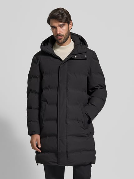 Männermodel trägt Steppmantel mit verdecktem Reißverschluss und Eingrifftaschen von MCNEAL in Schwarz, Regular Fit, Ganzkörperansicht von vorne.