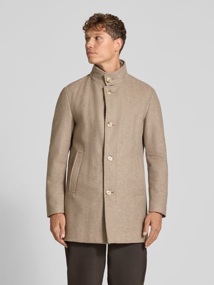 Männermodel trägt Mantel mit Stehkragen Modell 'Finlay 2.0' von Strellson in Beige, unifarben, strukturierte Optik, Ganzkörperansicht von vorne.