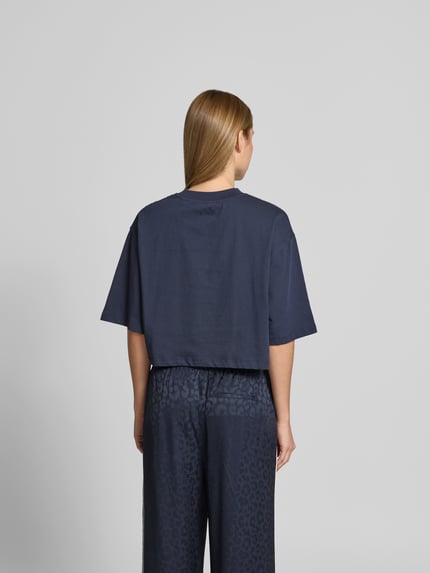 Frauenmodel trägt Cropped T-Shirt mit Logo-Print von Lala Berlin in Dunkelblau aus Reine Baumwolle, Halbarm, Rückenlänge 38 cm, Ganzkörperansicht Rückansicht.