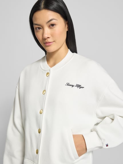Vrouwenmodel draagt Relaxed Fit Sweatjacke aus Baumwoll-Mix van Tommy Hilfiger in effen wit, logo-stitching, geribd, zijzakken, bovenlichaam close-up.