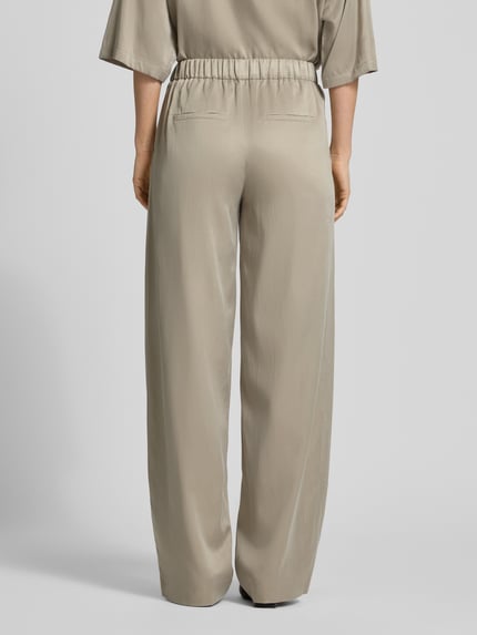 Kobiece model prezentuje Wide Fit Stoffhose mit elastischem Bund Modell 'Consider' von Drykorn, beżowy cupro-mix z bawełną, kieszenie z tyłu, szerokość w rozmiarze 27/34: 36 cm, długość nogawki 84 cm, widok całej sylwetki z tyłu.