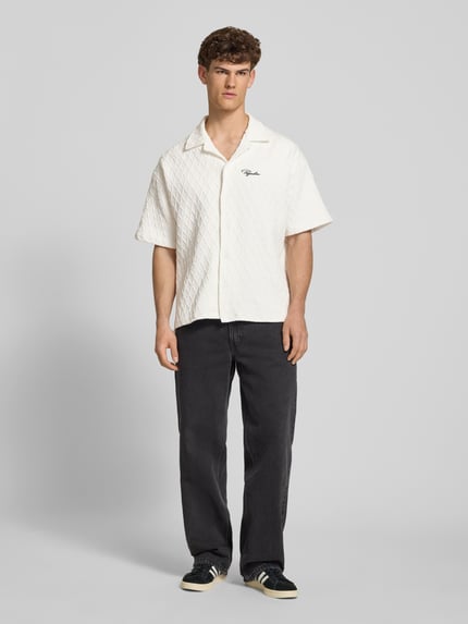 Männermodel trägt Regular Fit Freizeithemd mit Label-Stitching Modell 'Jovren' von Pegador aus Elastischer-Material-Mix, Halbarm, Reverskragen, Knopfleiste in Creme mit strukturierter Oberfläche, schwarze Hose, Ganzkörperansicht von vorne. Rückenlänge bei Größe M: 72 cm, Schulterbreite bei Größe M: 45 cm, Ärmellänge bei Größe M: 33 cm.