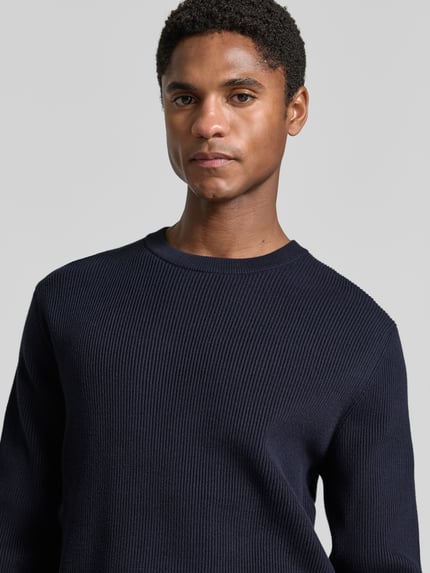 Männermodel trägt Slim Fit Strickpullover Baumwoll-Mix von Lindbergh, gerippte Optik, Rundhalsausschnitt, Nahaufnahme Oberkörper.