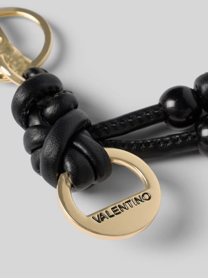 Produktfoto, złoty brelok do kluczy z ozdobnymi kamieniami, czarne skórzane elementy, model 'Eloura' od VALENTINO BAGS, detal z logo