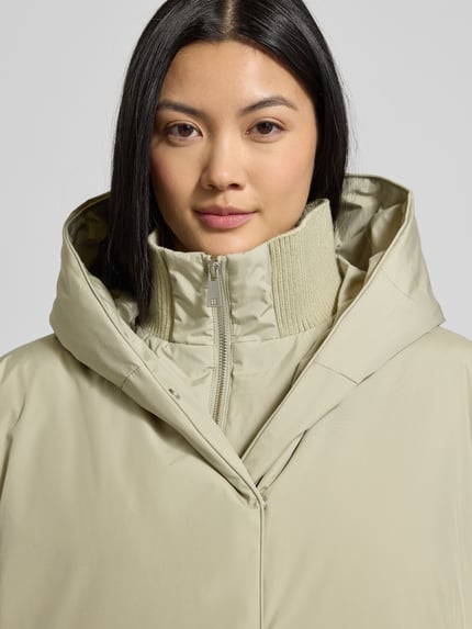 Frauenmodel trägt Regular Fit Outdoor-Jacke mit Stehkragen Modell 'Helah' von Opus, beige mit Kapuze, elastische Ärmelabschlüsse, Nahaufnahme Oberkörper. Rückenlänge 74 cm, Schulterbreite 53 cm, Brustweite 54 cm, Ärmellänge 63 cm bei Größe 36.