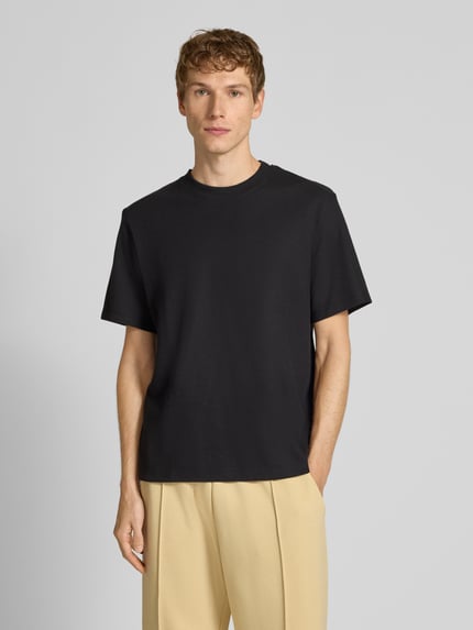Mężczyzna model nosi T-Shirt mit Stehkragen Modell 'AUSTIN' od Jack & Jones, czarny, bawełniany, prosty krój, ujęcie całej sylwetki od przodu.