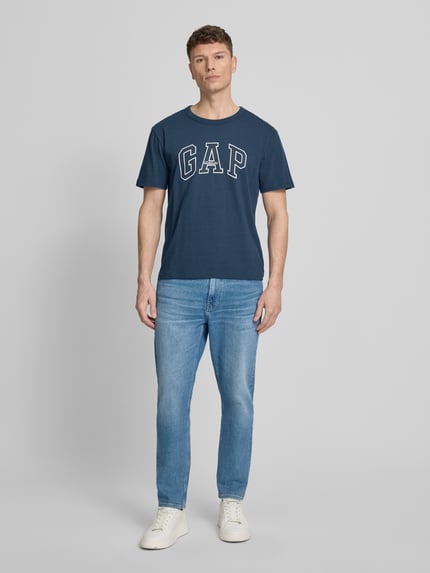 Männermodel trägt T-Shirt mit Logo und Rundhalsausschnitt von GAP in Blau, Reine Baumwolle, Regular-Fit, Rückenlänge 66 cm, Ganzkörperansicht von vorne.