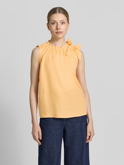 Vrouwenmodel draagt Regular Fit blouse uit viscosemix met linnen van Christian Berg Woman, sierstrik, opstaande kraag met ruches, mouwloos design, ruglengte bij maat 36: 54 cm, effen lichtoranje kleur, rechte vorm, licht getextureerde stof, voorkant volledige lichaamsweergave.
