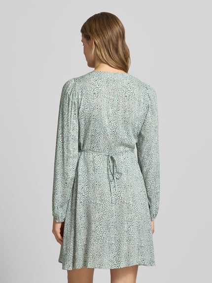 Modelka kobieca ma na sobie tailliertes Freizeitkleid aus reiner Viskose Modell 'EVIDA' od Only, efekt: wzór na całej powierzchni, mini, dekolt w serek, listwa guzikowa, długi rękaw, bufiaste rękawy, zakończenie rękawów: guzik z oczkiem, materiał: wiskoza, widok całej sylwetki z tyłu.