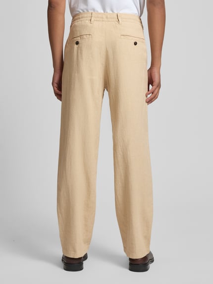 Männermodel trägt Loose Fit Leinenhose mit Tunnelzug Modell 'BRODY' von Selected Homme, Optik: Unifarben, Bio-Baumwoll-Leinen-Mix, Flammgarn, Gesäßtaschen mit Knopf, helle Cremefarbe, strukturierte Textur, Ganzkörperansicht Rückansicht.