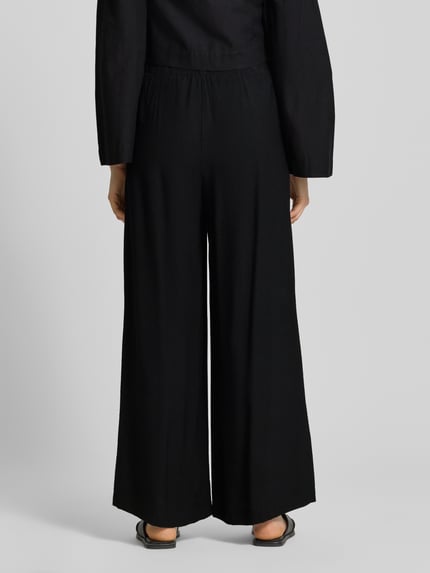 Modelka nosi Wide Fit Stoffhose aus Viskose-Mix Modell 'Frencis' od STEHMANN, czarny kolor, szerokie nogawki, elastyczny pas, kieszenie, Szerokość w rozmiarze 36: 38 cm, długość nogawki od wewnątrz: 77 cm, widok całej sylwetki z tyłu.