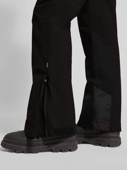 Männermodel trägt Flared Stoffhose mit Reißverschlusstaschen Modell 'KUMPULA' von LUHTA in Schwarz, Detailaufnahme der Beine.
