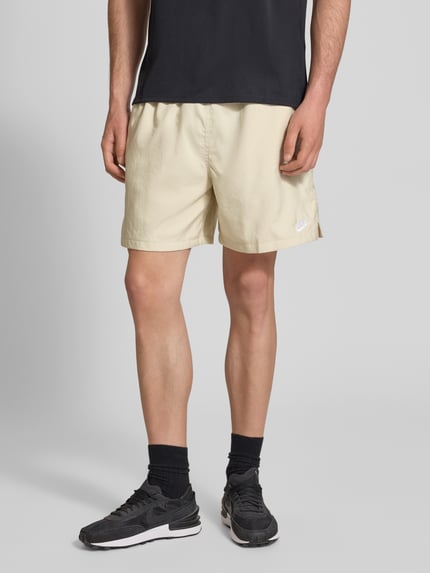 Männermodel trägt Shorts mit Label-Stitching und elastischem Bund von Nike in Beige, Regular-Fit, Tunnelzug, Nahaufnahme Oberschenkel.