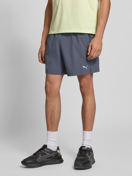 Mężczyznamodel nosi szorty z elastycznym pasem i logo od PUMA PERFORMANCE, mieszanka materiałów z dodatkiem streczu, krój regular fit, szerokość w rozmiarze M: 39 cm, długość wewnętrzna nogawki: 19 cm, widok całej sylwetki z przodu.