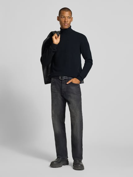 Męski model nosi Slim Fit Rollkragenpullover aus Woll-Mix Modell 'Karl' von Casual Friday, czarny, prążkowane wykończenia, długi rękaw, prążkowany kołnierz, mieszanka wełny, całkowita długość z tyłu w rozmiarze M: 70 cm, długość rękawa w rozmiarze M: 69 cm, widok całej sylwetki z przodu.