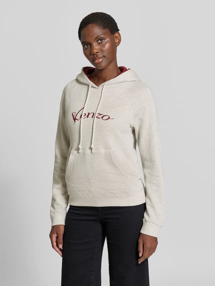 Kobiece modelka nosi Hoodie aus reiner Baumwolle od KENZO w kolorze jasnoszarym, nadruk z logo, kaptur w kontrastowym kolorze, kieszeń kangurka, taliowany krój, długość tyłu 60 cm w rozmiarze S, widok całej sylwetki z przodu