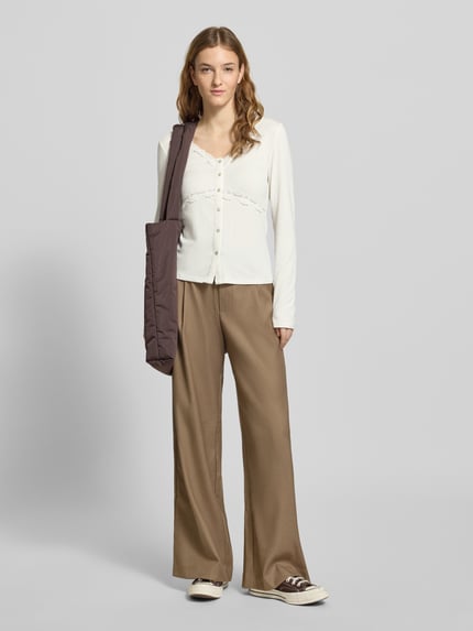 Frauenmodel trägt Slim Fit Langarmshirt aus Viskose-Mix Modell 'SINI' von Only, unifarben mit Knopfleiste, V-Ausschnitt, Spitze, Ganzkörperansicht von vorne.